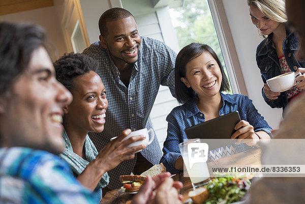Eine Gruppe von Menschen  die sich in einem Cafe trifft. Mit digitalen Tablets und Smartphones.