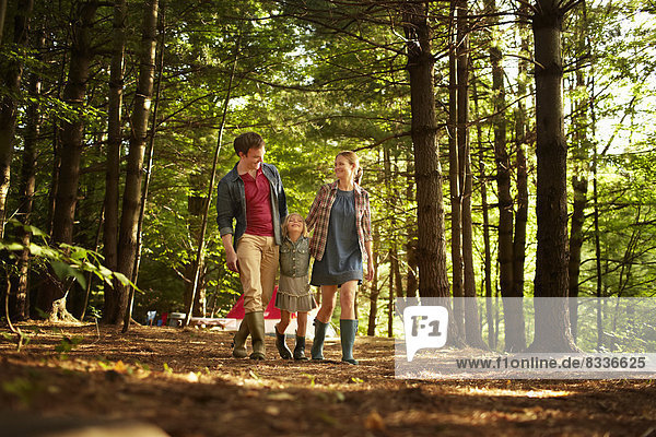 Drei Personen  eine Familie  die am späten Nachmittag im Wald spazieren geht.