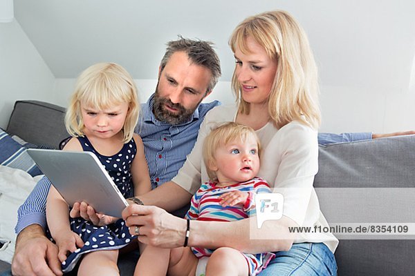 Parents with two children using digital tablet