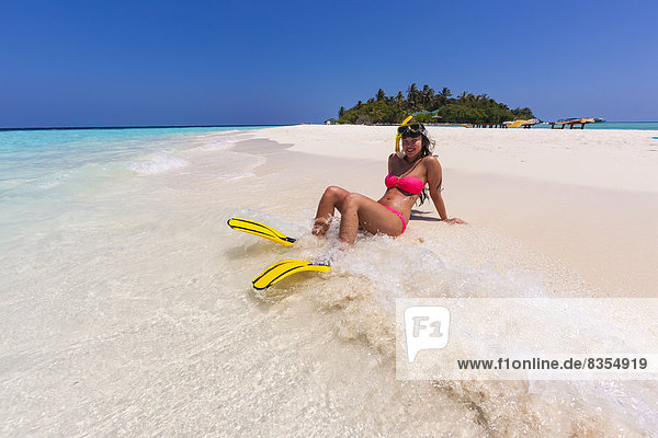 Woman with flippers and diving goggles sitting on a sand bank  Indian Ocean  Maldives