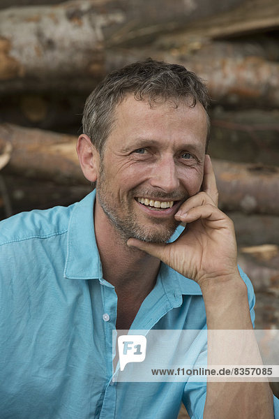 Lächelnder Mann beim Holzhaufen