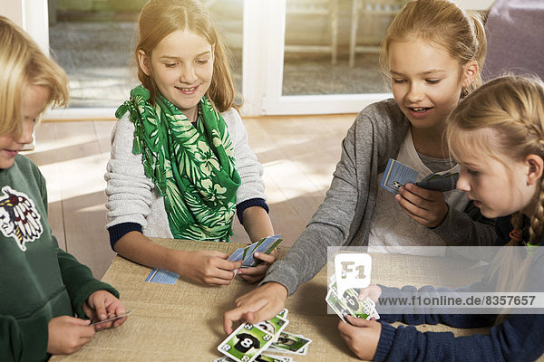 Vier Kinder spielen Kartenspiel im Wohnzimmer