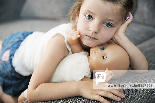 Porträt eines kleinen Mädchens auf dem Sofa mit ihrer Puppe  Nahaufnahme
