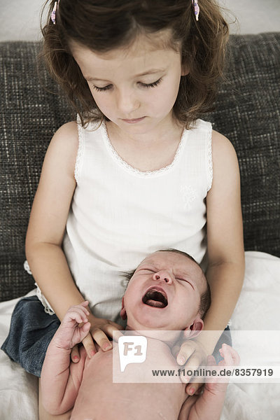 Kleines Mädchen und ihr weinender neugeborener Bruder zu Hause