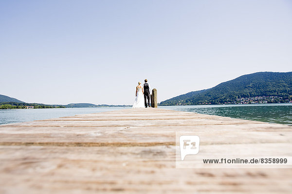 Germany  Bavaria  Tegernsee  Wedding couple standing on jetty