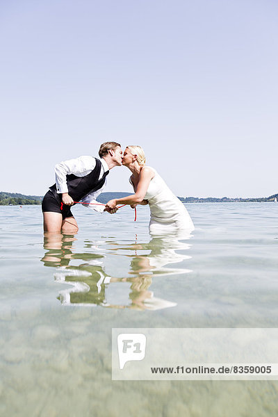 Germany,  Bavaria,  Tegernsee,  Wedding couple standing in lake,  kissing
