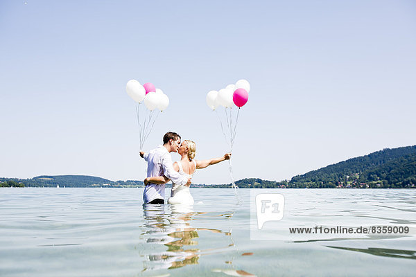 Germany,  Bavaria,  Tegernsee,  Wedding couple standing in lake,  kissing