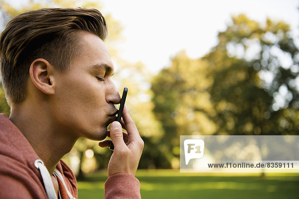 Young man kissing his smart phone  close-up