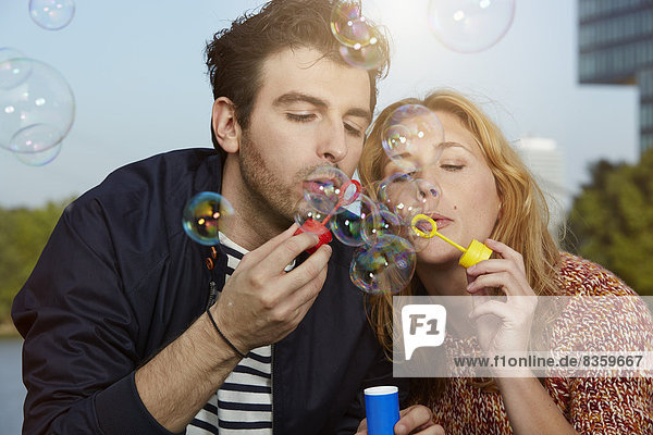 Germany  Dusseldorf  Young couple making soap bubbles