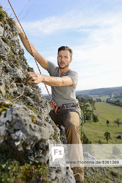 Mann klettert auf einem Felsen