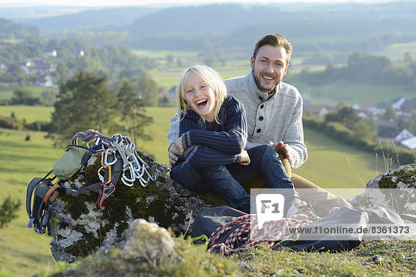 Father and son sitting on a rock with climbing equipment