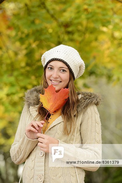 Lächelnde junge Frau mit Herbstblatt  Portrait