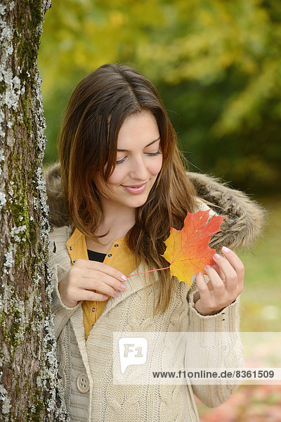 Lächelnde junge Frau mit Herbstblatt