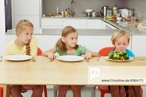 Kinder starren auf den vollen Teller voller Grüns