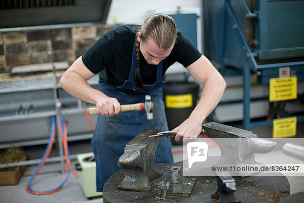 Man using hammer for metalworking in creative studio