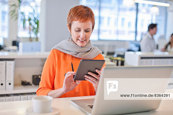 Businesswoman sitting at table using digital tablet