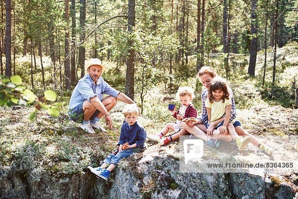 Family sitting on rocks in forest