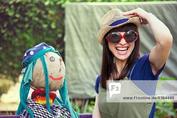 Frau mit Sonnenbrille und Hut mit Vogelscheuche