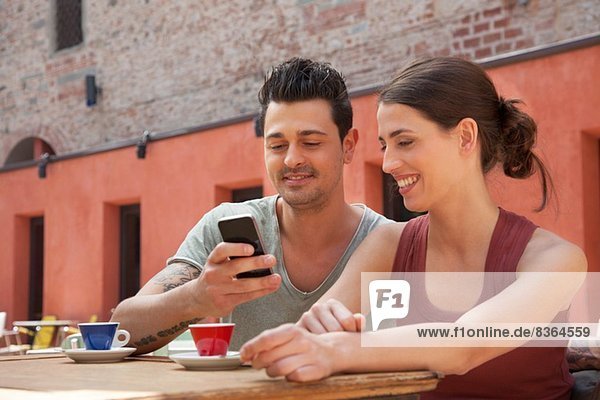Ehepaar benutzt Smartphone vor einem Café  Florenz  Toskana  Italien