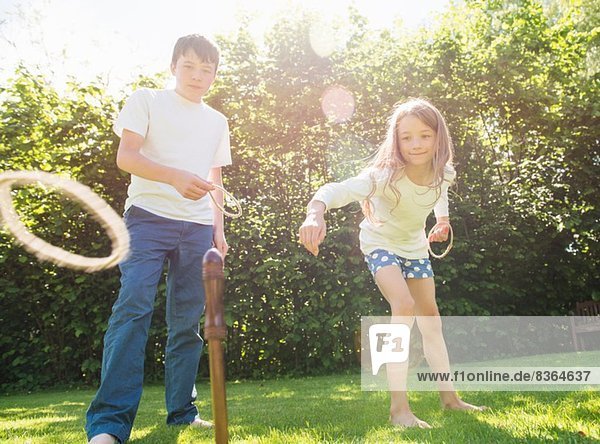 Bruder und Schwester spielen Hoopla im Garten