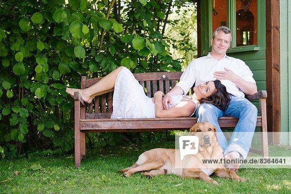 Portrait eines reifen Paares auf einer Gartenbank mit Hund
