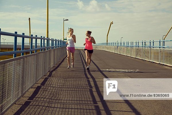 Junge Joggerinnen laufen auf der Brücke