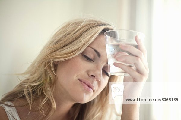 Nahaufnahme Porträt einer jungen Frau mit einem Glas Wasser