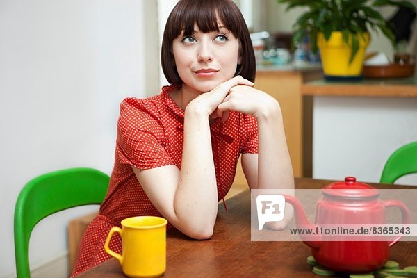 Porträt einer jungen Frau am Küchentisch sitzend