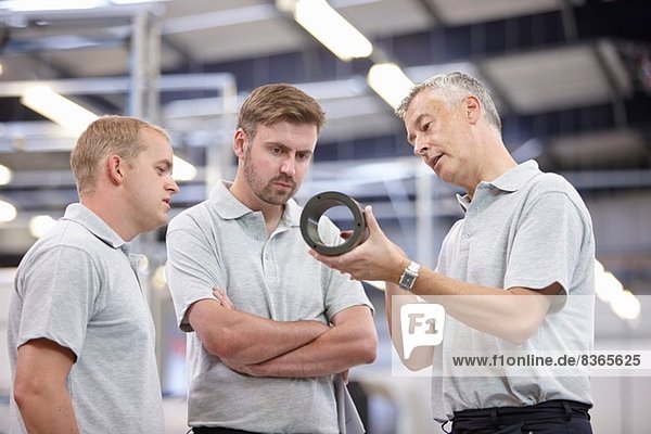 Manager discussing component in engineering factory