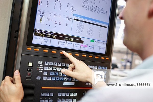 Worker checking computer monitor in engineering factory
