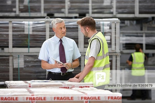 Warehouse worker and manager discussing order in engineering warehouse