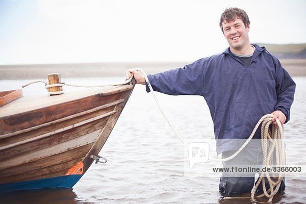 Porträt eines Mannes  der sich am Ruderboot lehnt  Wales  UK