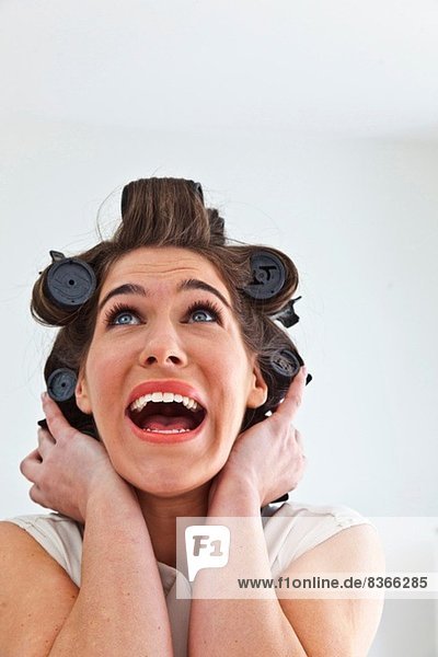 Junge Frau mit Haarrollen die nach oben schaut.