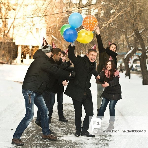 Gruppe junger Freunde mit Partyhüten und Ballons