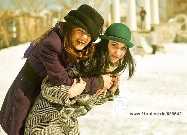 Zwei junge Frauen  die im Schnee herumalbern.