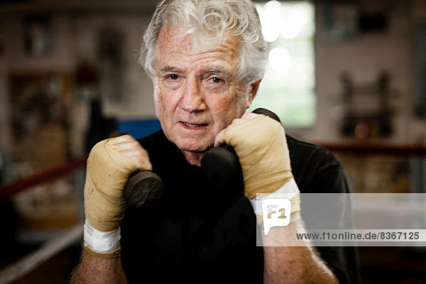 Älterer Mann mit Handschuhen  Gewichtheben