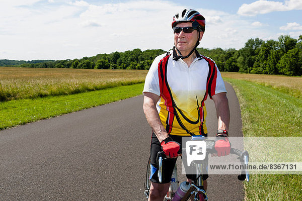 Senior man riding bicycle through countryside