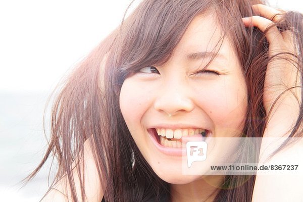 Porträt einer jungen Frau  Hände im Haar  Zunge herausstreckend