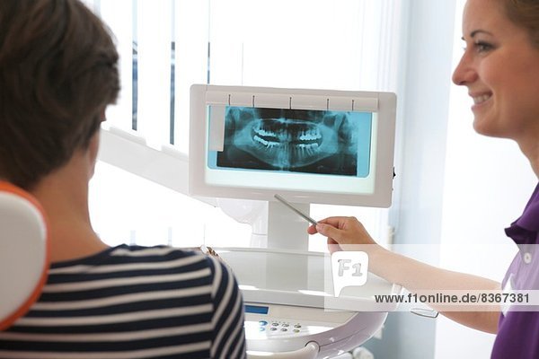 Patient betrachtet Röntgenbild von Zahnimplantaten