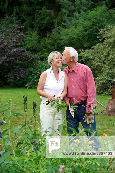 Porträt eines älteren Paares  das einen Kuss im Garten teilt
