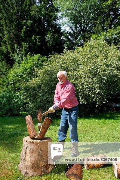 Senior Mann beim Holzhacken im Garten