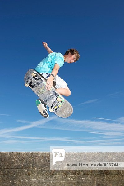 Teenager Junge in der Luft auf dem Skateboard