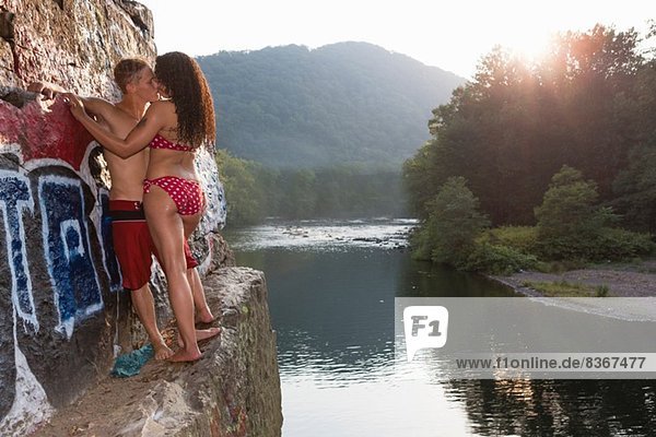 Young couple sharing a kiss on rock ledge  Hamburg  Pennsylvania  USA