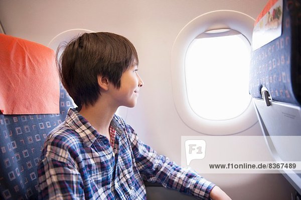 Junge blickt aus dem Fenster im Flugzeug