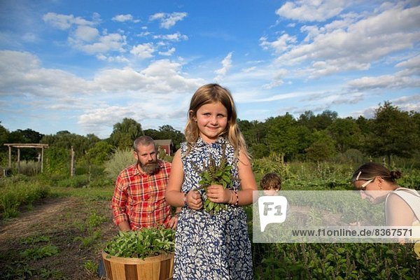Porträt eines Mädchens  das einen Haufen Blätter auf einer Familien-Kräuterfarm hält