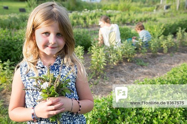 Porträt eines Mädchens mit Laubbüscheln auf einer Kräuterfarm