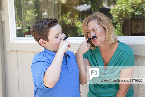 A Mother And Son Hold Moustaches Up To Their Faces Pacifica  California  United States Of America