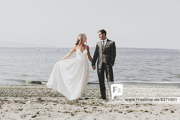 A Bride And Groom On A Beach At The Water's Edge Kirkland  Washington  United States Of America