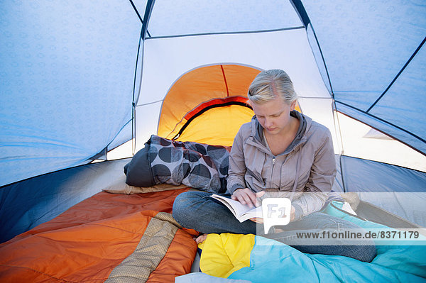 A Young Woman Reading A Book Inside A Tent California  United States Of America