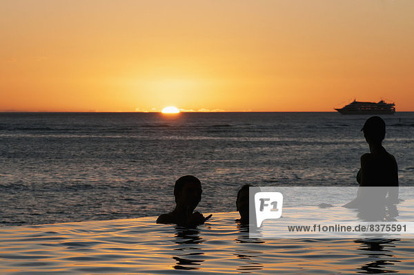 People In An Infinity Pool At The Water's Edge At Sunset Over Waikiki Beach  Honolulu  Oahu  Hawaii  United States Of America